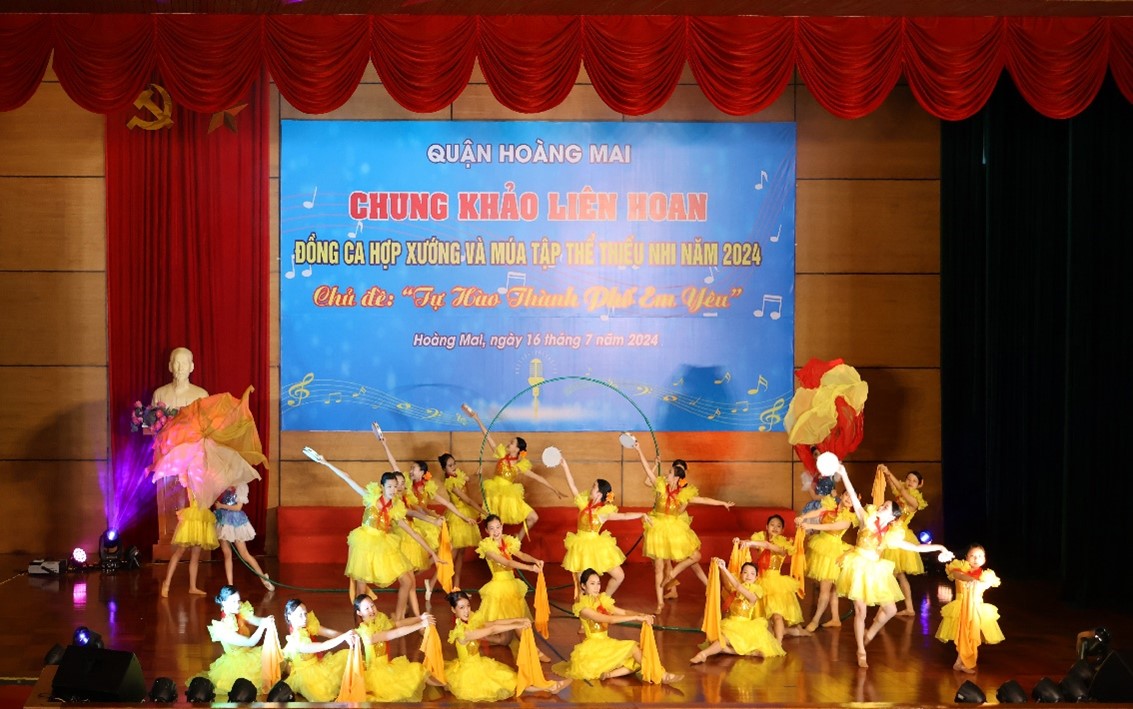 A group of people in yellow dresses on a stageDescription automatically generated